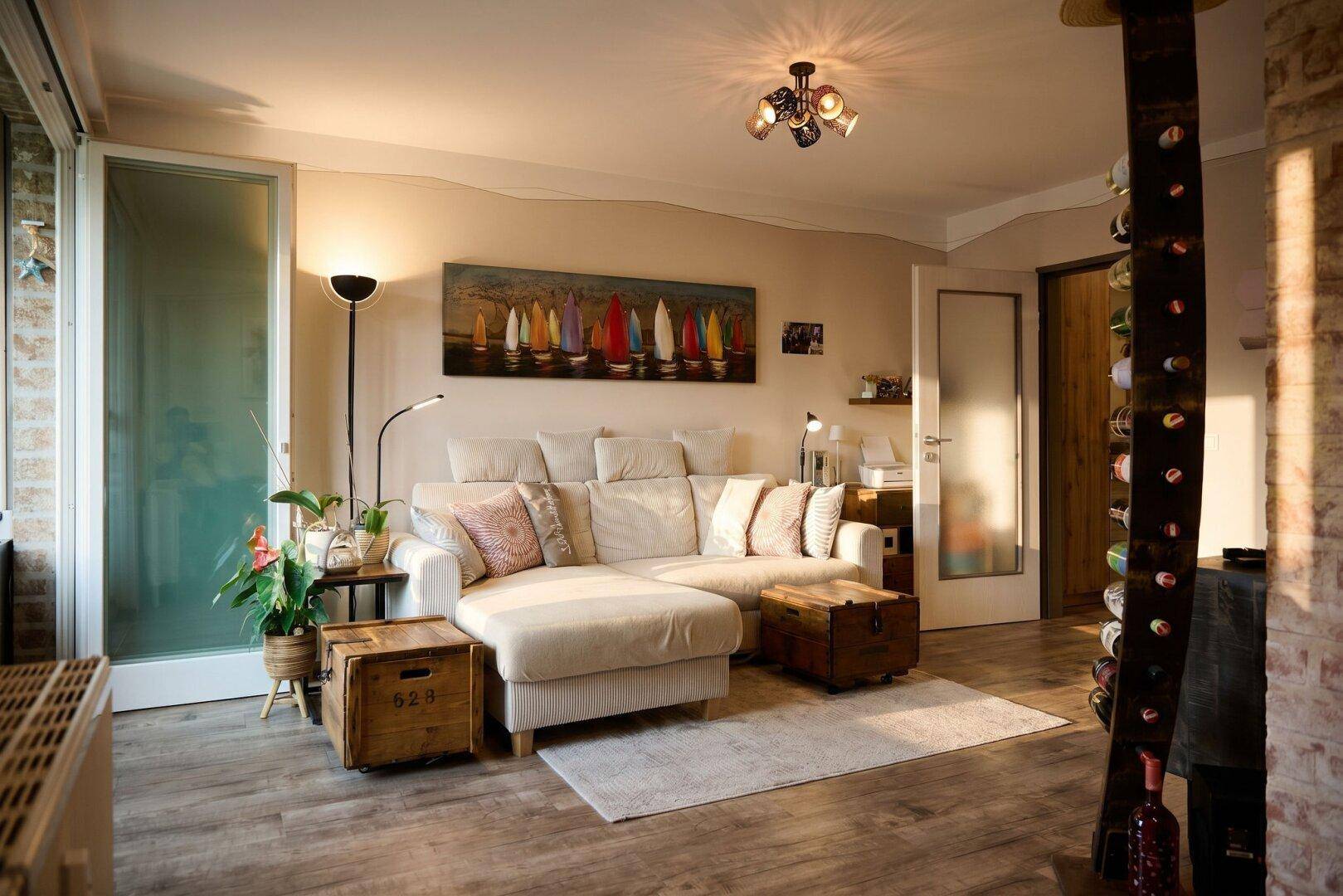 Gemütliches Wohnzimmer mit großem Sofa, Holzboden und Zugang zu einem Außenbereich.