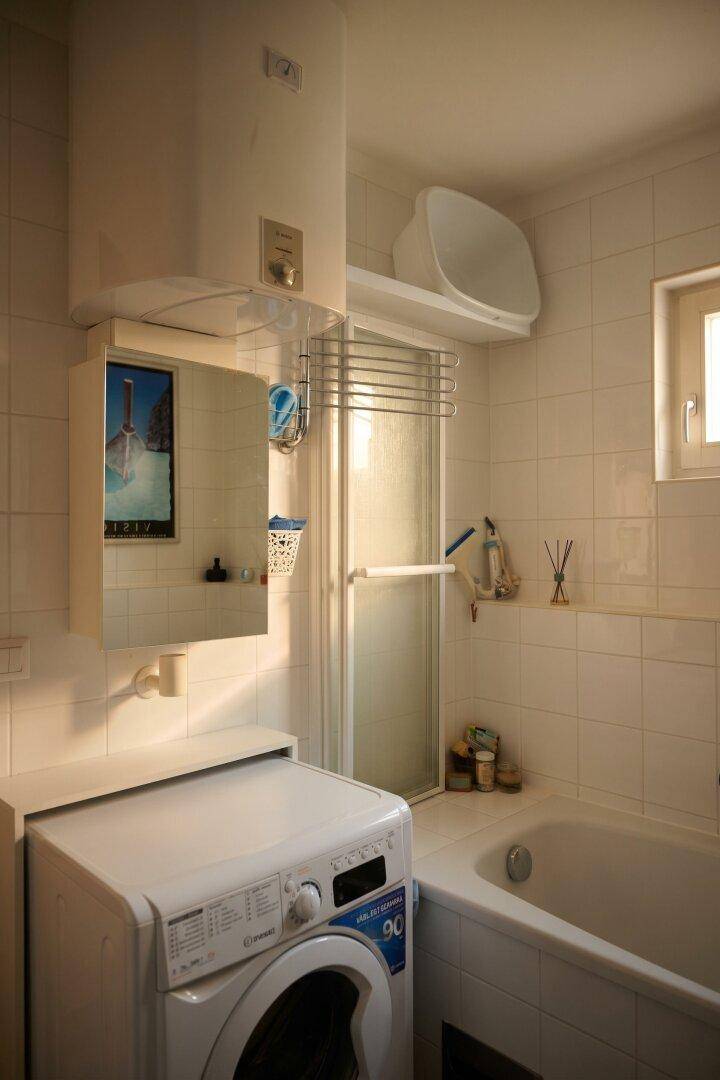 Funktionales Badezimmer mit Waschmaschine, Badewanne und Duschkabine.