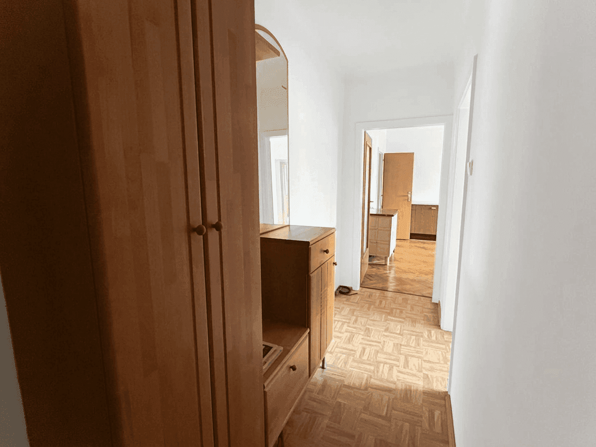 Heller Flur mit Parkettboden und einem Holzschrank, der zu anderen Räumen führt.