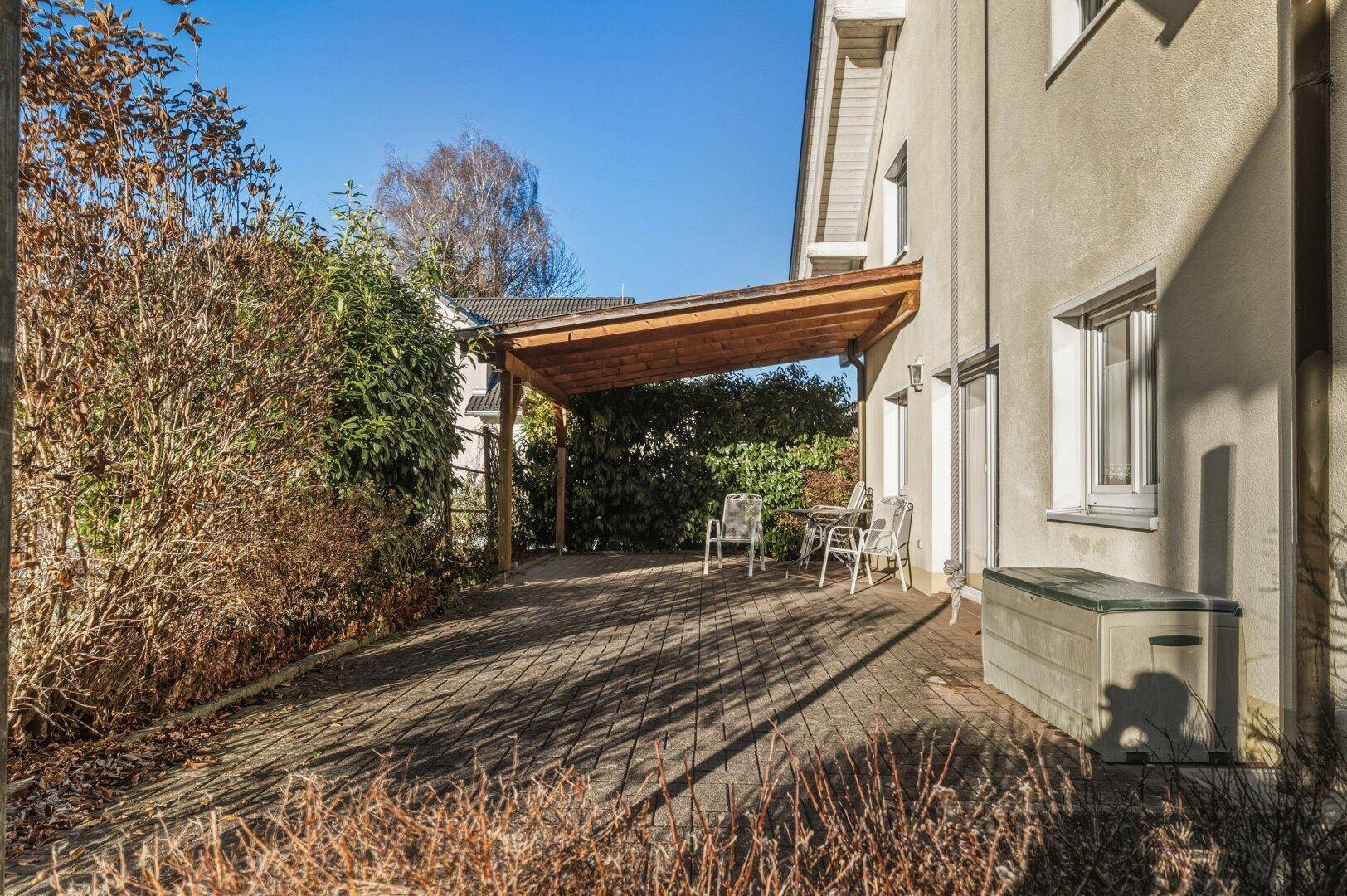 Überdachte Terrasse mit Holzdach und Gartenmöbeln, ideal für entspannte Stunden im Freien.