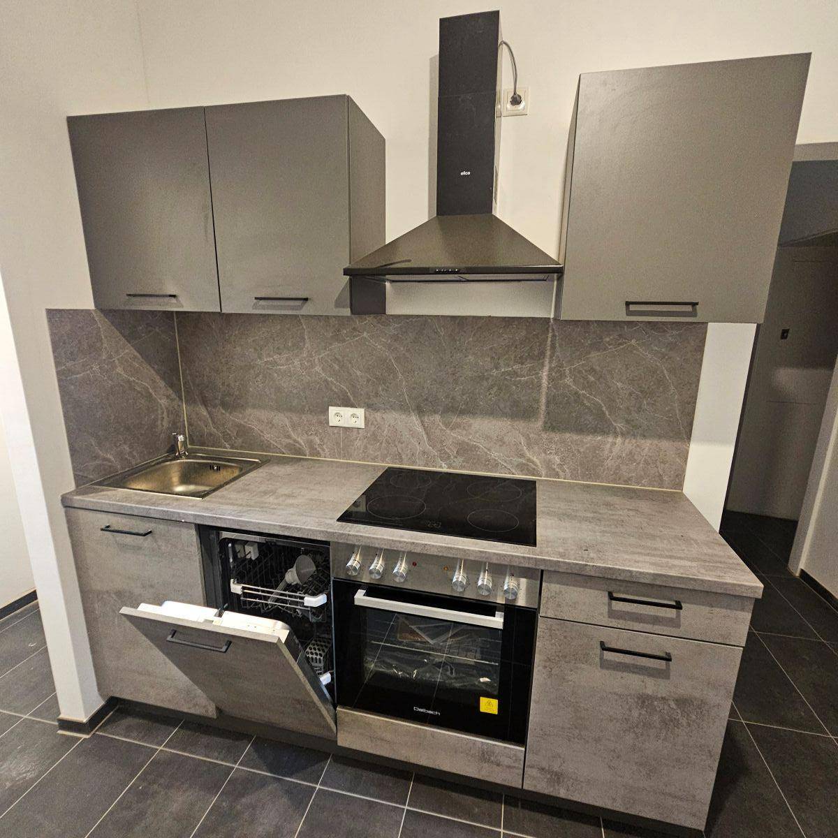 Moderne Einbauküche in Grau mit Induktionskochfeld, Backofen, Geschirrspüler und Dunstabzugshaube.