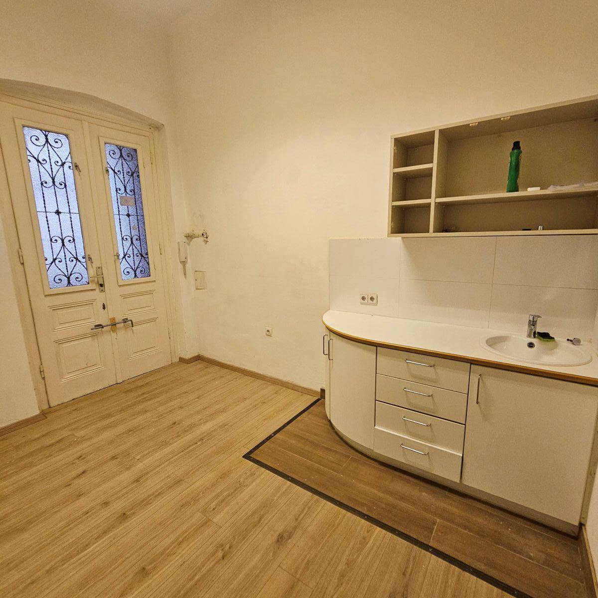 Küchenzeile mit Spüle und Schränken in einem Raum mit Laminatboden und einer Doppeltür.