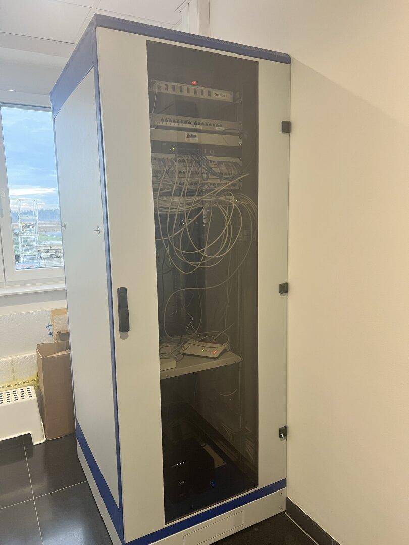 Server-Schrank mit Verkabelung und Netzwerkgeräten in einem Technikraum.