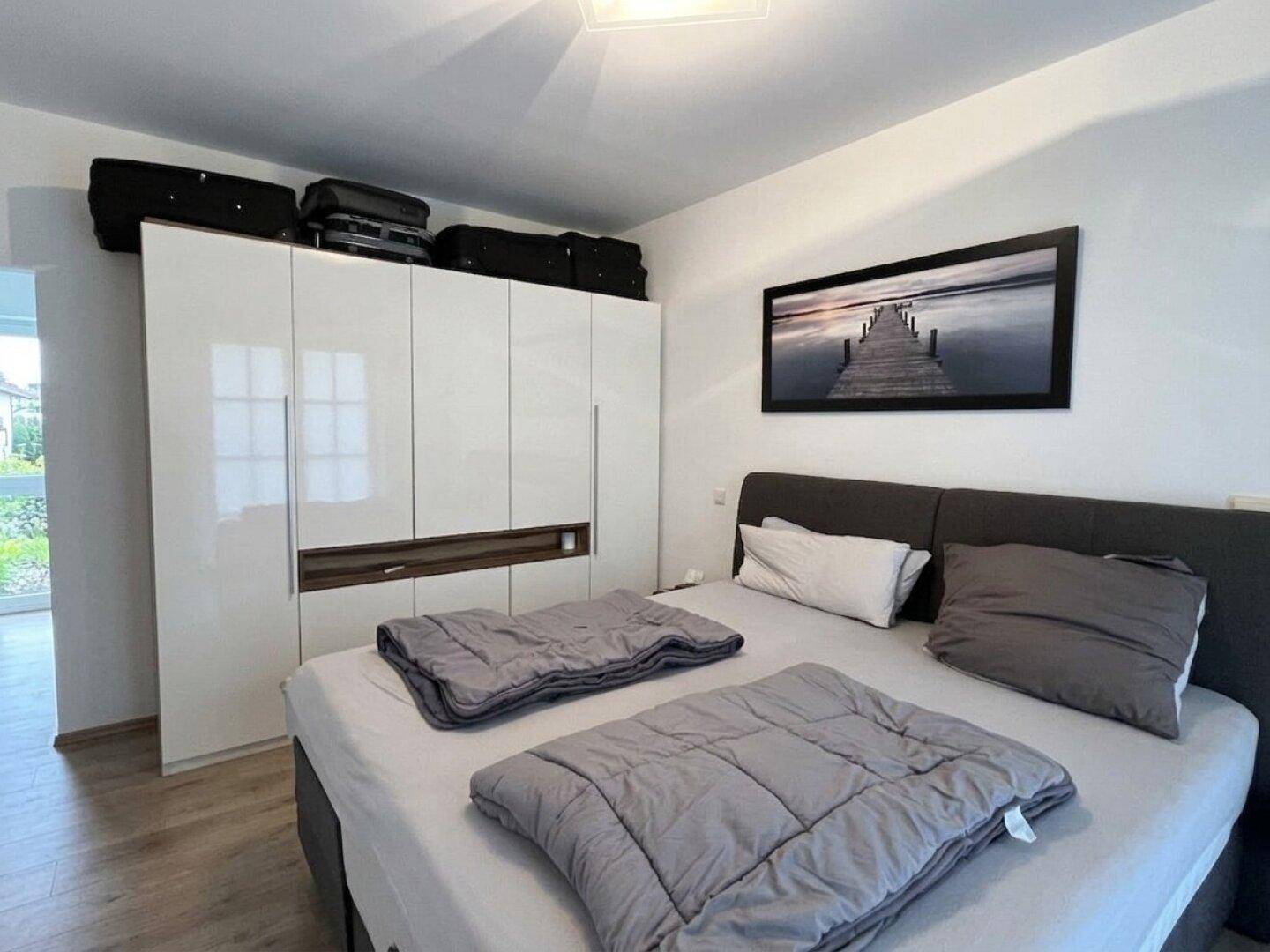 Schlafzimmer mit Doppelbett und einem großen, glänzenden Kleiderschrank.