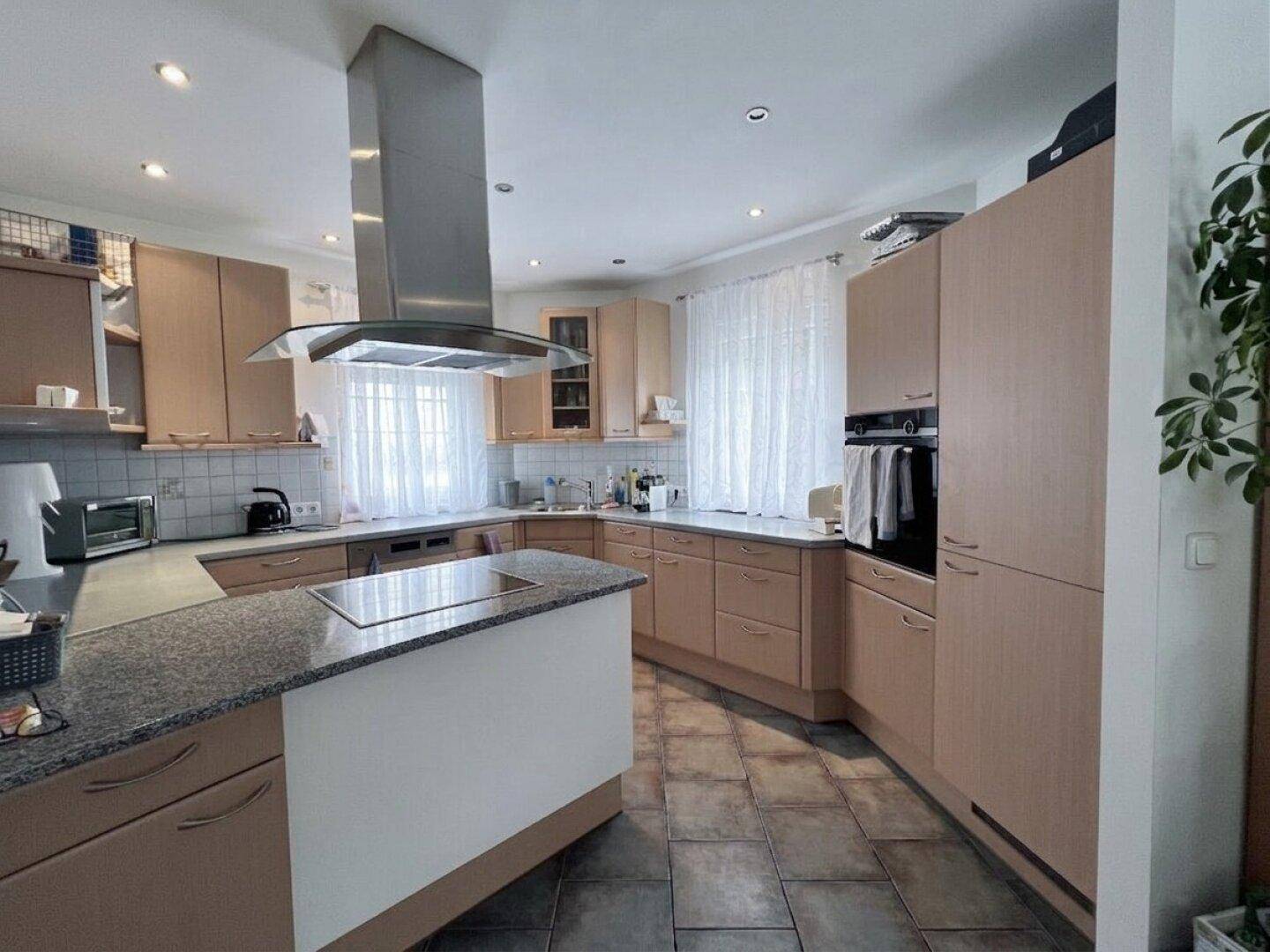 Geräumige Küche mit Holzschränken, Kochinsel und Granitarbeitsplatten in hellem Design.