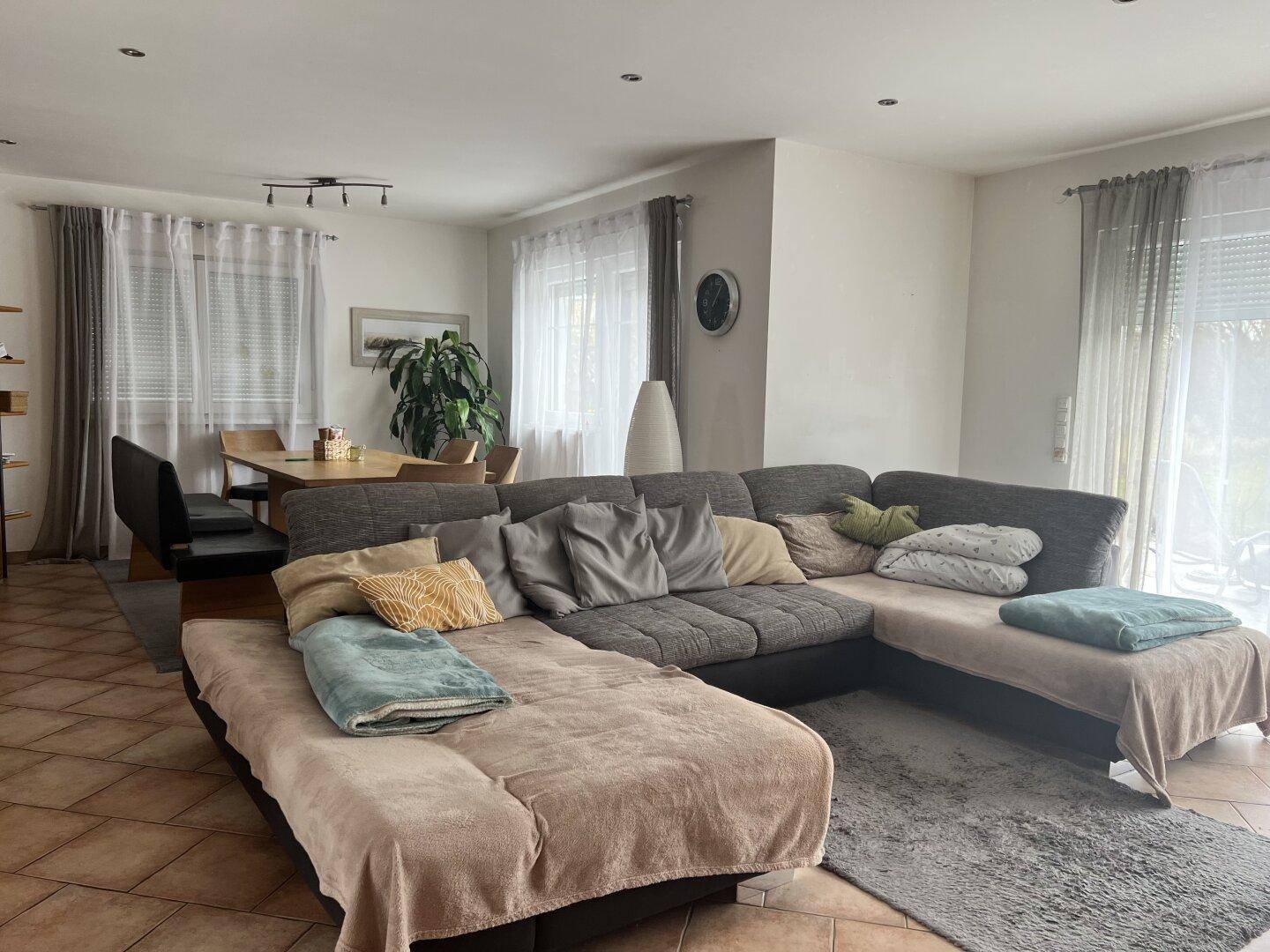 Gemütlicher Wohnbereich mit großem Ecksofa und Zugang zur Terrasse, offen zum Essbereich.