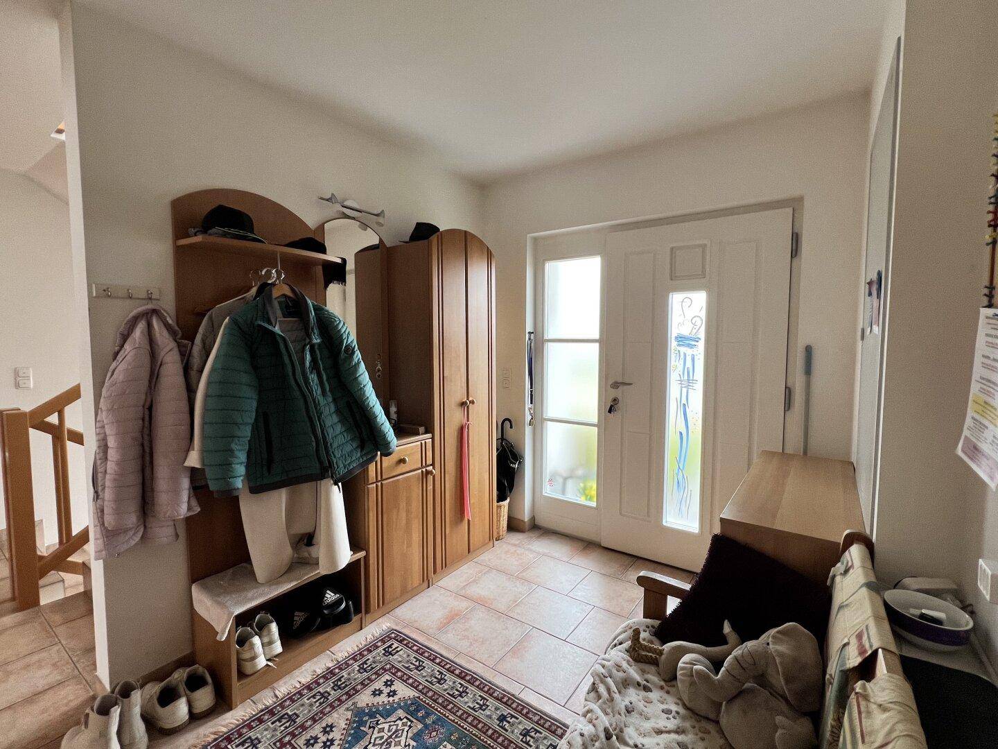 Eingangsbereich mit Garderobe, Schuhschrank und gefliestem Boden, einladend gestaltet.