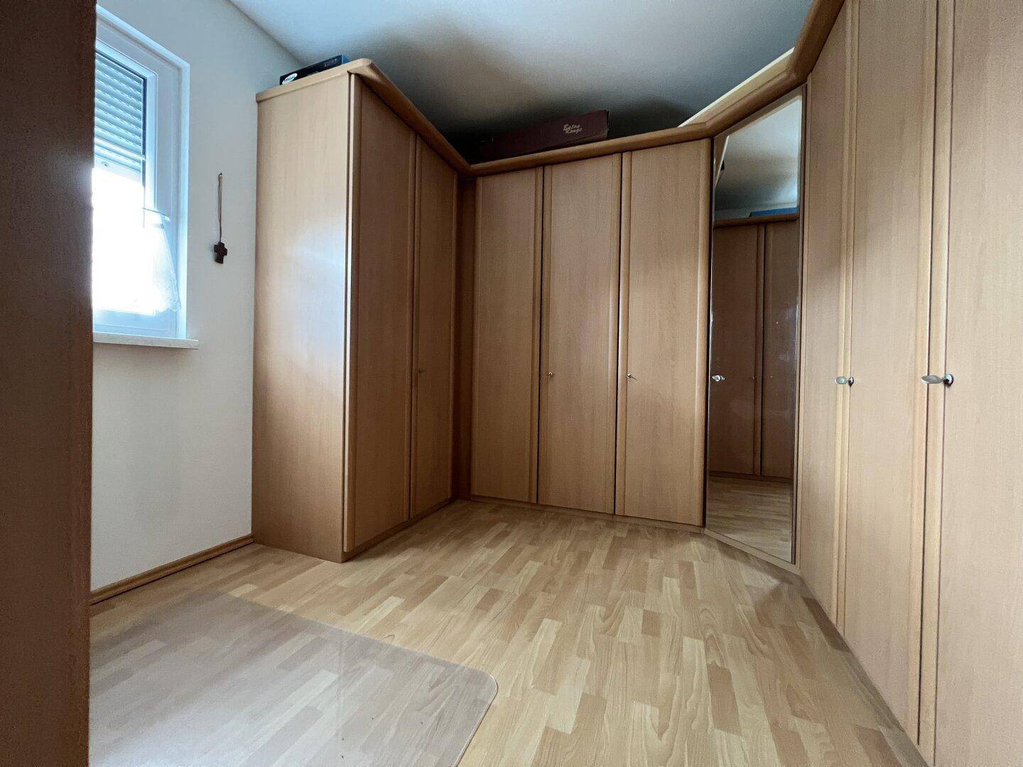 Schlafzimmer mit Einbauschränken und hellem Laminatboden, bietet viel Stauraum.