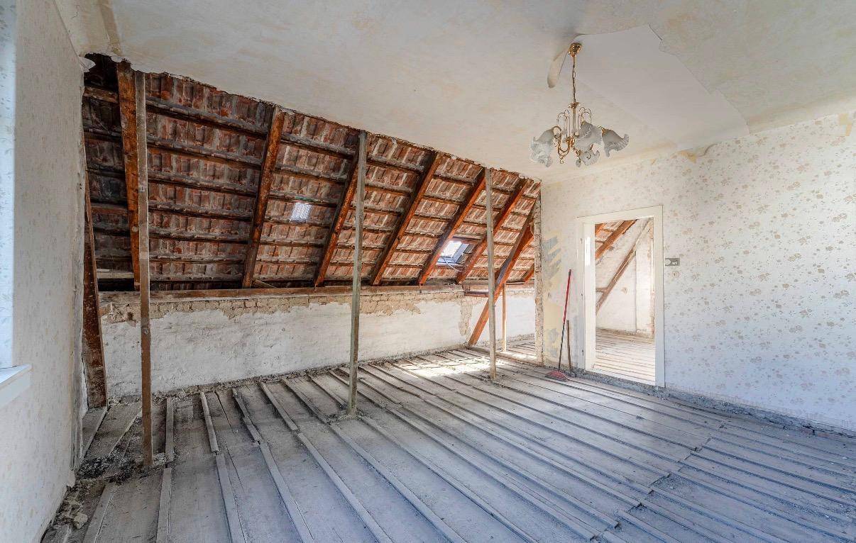 Geräumiger Dachboden im Rohzustand mit sichtbaren Dachbalken und Holzboden.