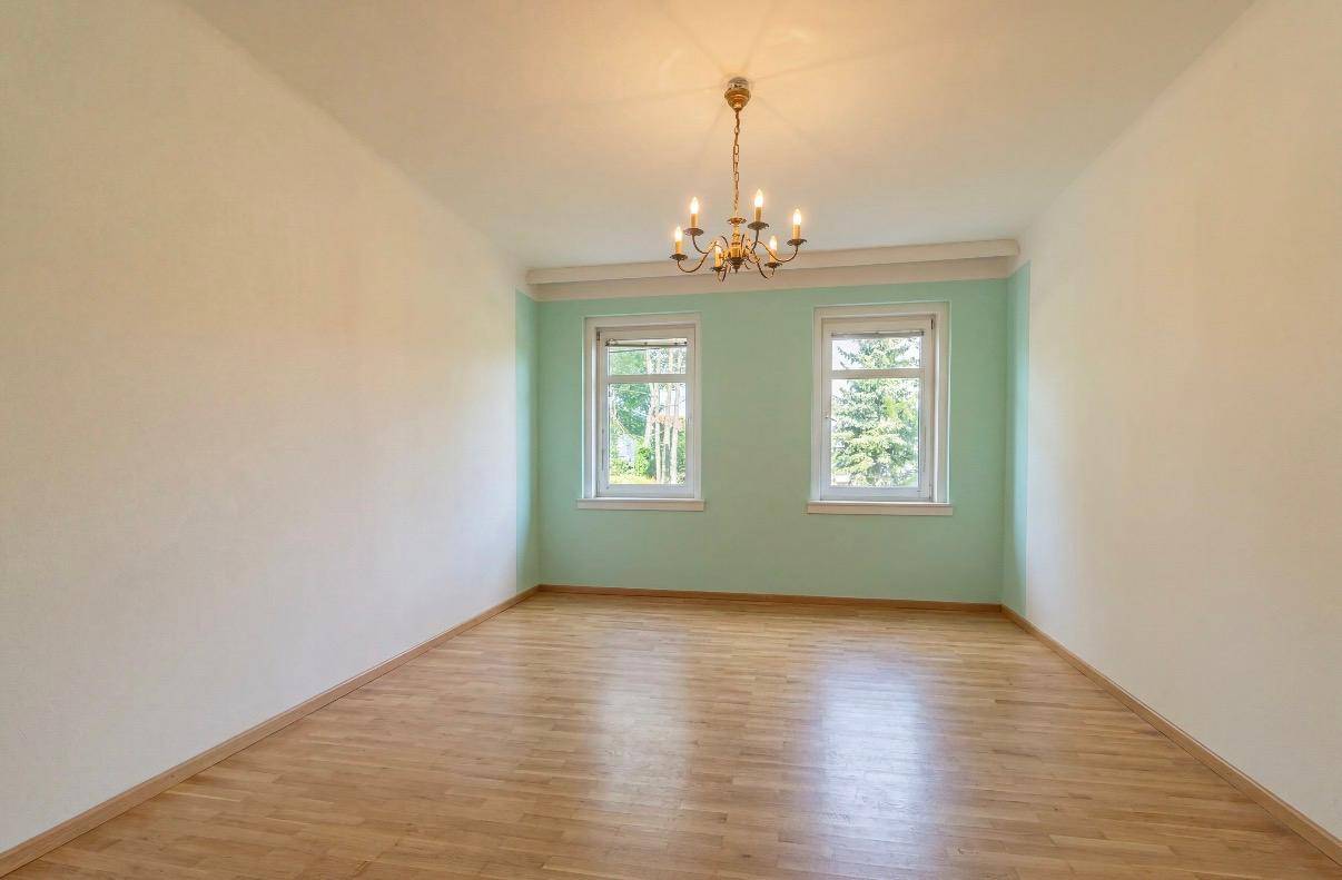 Renoviertes Zimmer mit hellem Parkettboden und mintgrüner Akzentwand.