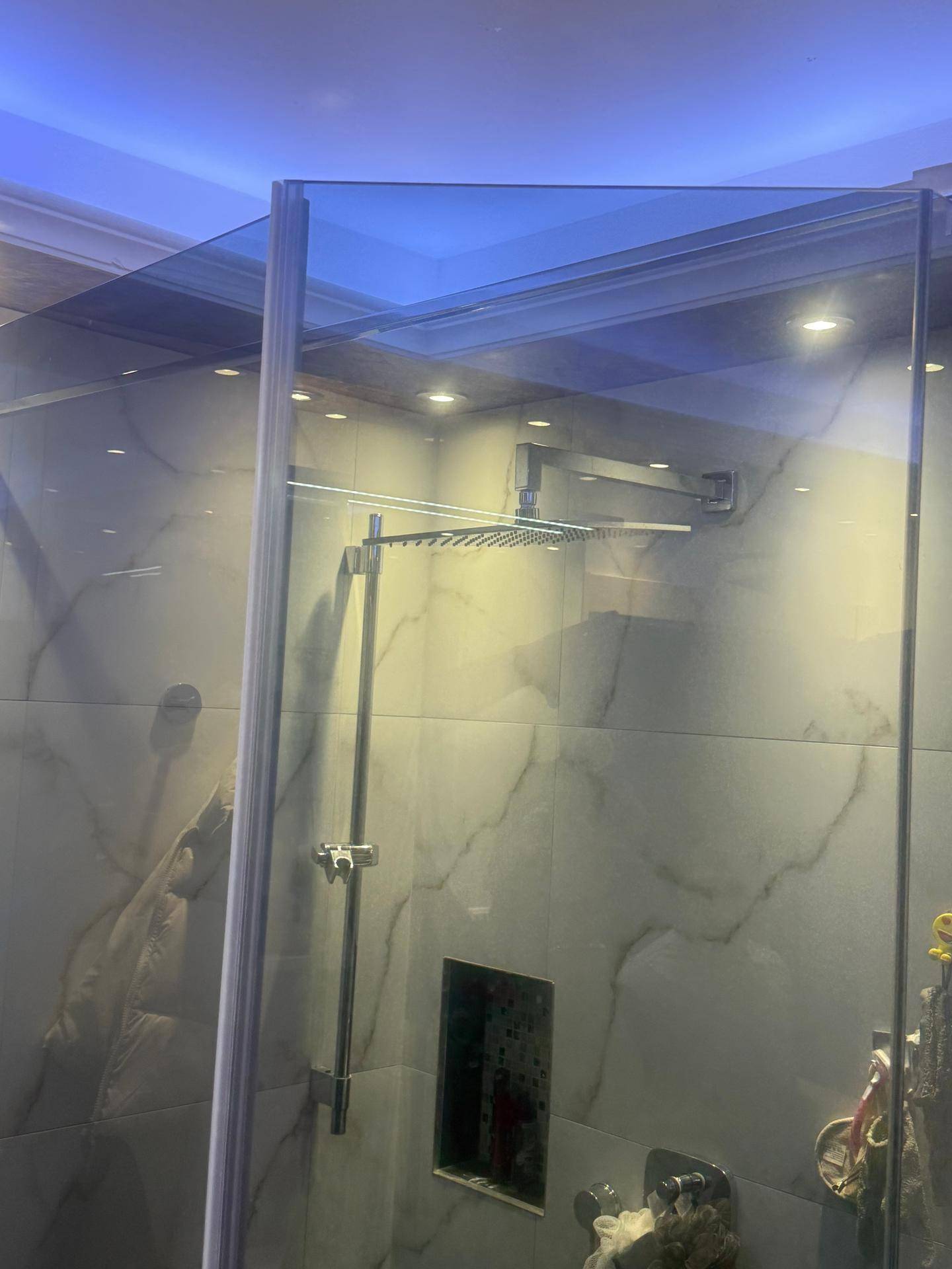 Moderne Duschkabine mit Regendusche und eleganten Marmorfliesen an den Wänden.