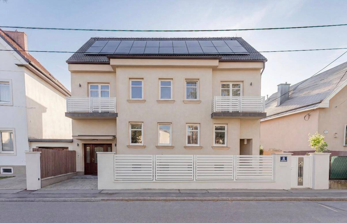 Vorderansicht des Hauses mit Solaranlage auf dem Dach und Balkonen.
