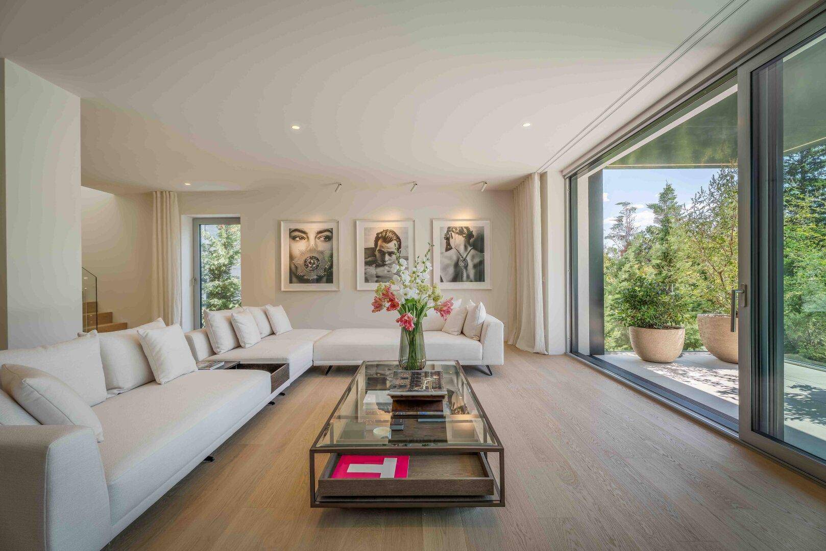 Elegantes Wohnzimmer mit bequemen Sofas und einer großen Glasfront mit Blick auf die Terrasse.