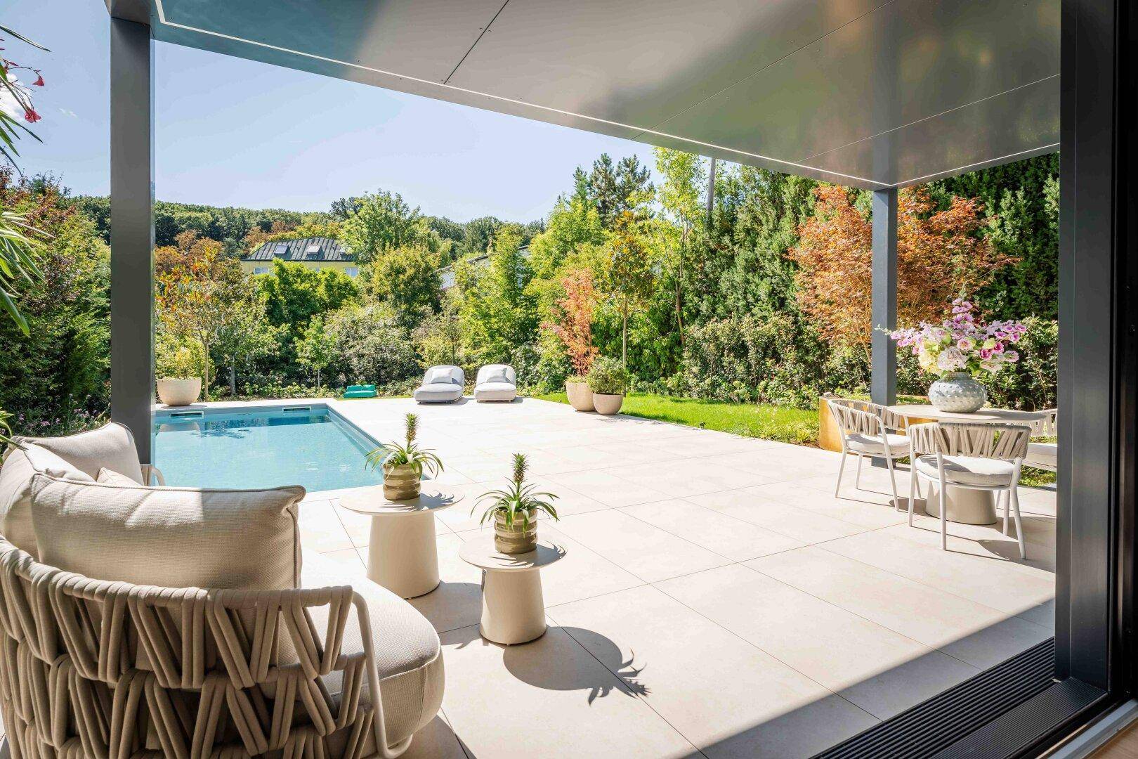Große überdachte Terrasse mit Poolblick und bequemen Loungemöbeln für entspannte Stunden.