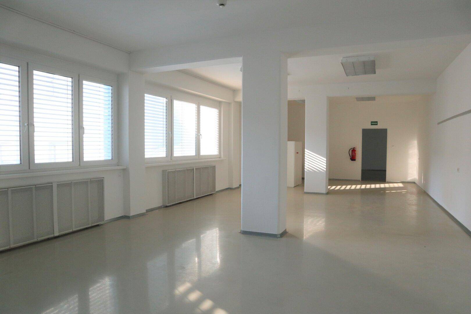 Geräumiger Büroraum mit vielen Fenstern, Jalousien und Säulen, bietet viel Tageslicht und Flexibilität.