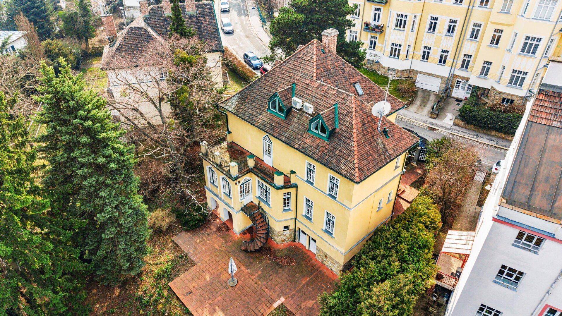 Luftaufnahme des historischen Gebäudes mit Mansarddach und umliegender grüner Landschaft.
