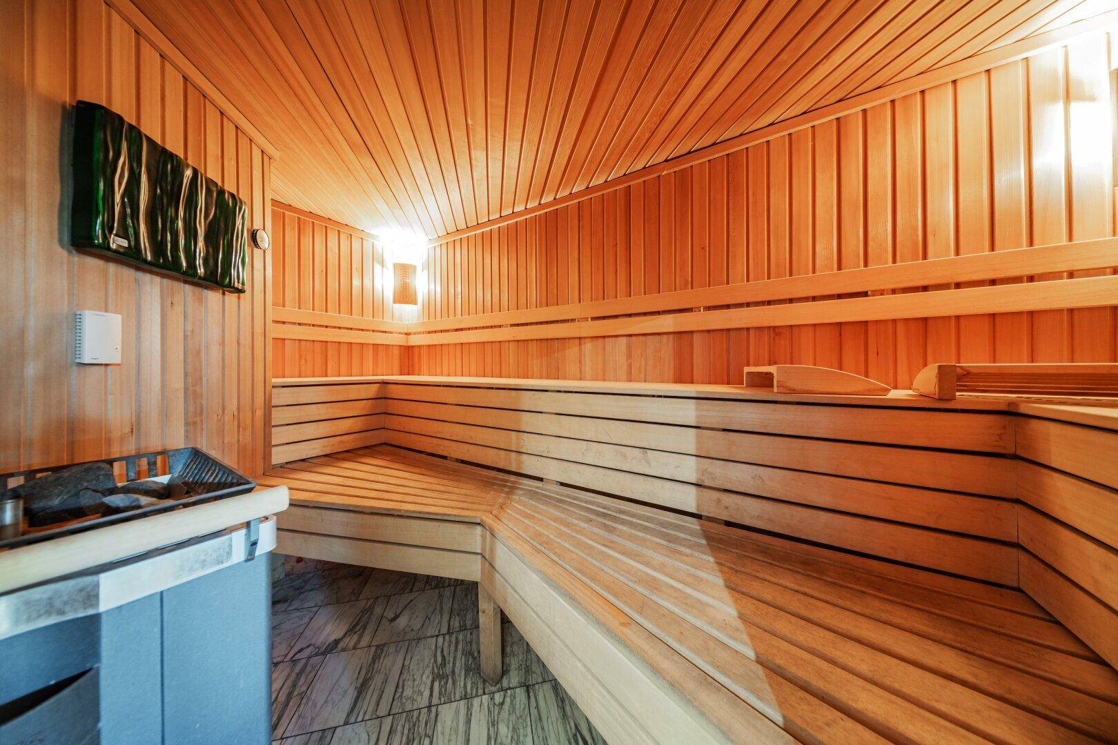 Gemütliche Holzsauna mit Bänken und traditionellem Saunaofen für Entspannung.