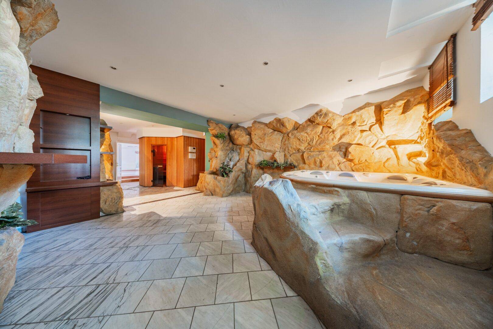 Exklusiver Wellnessbereich mit Whirlpool, Steindekoration und Zugang zur Sauna.
