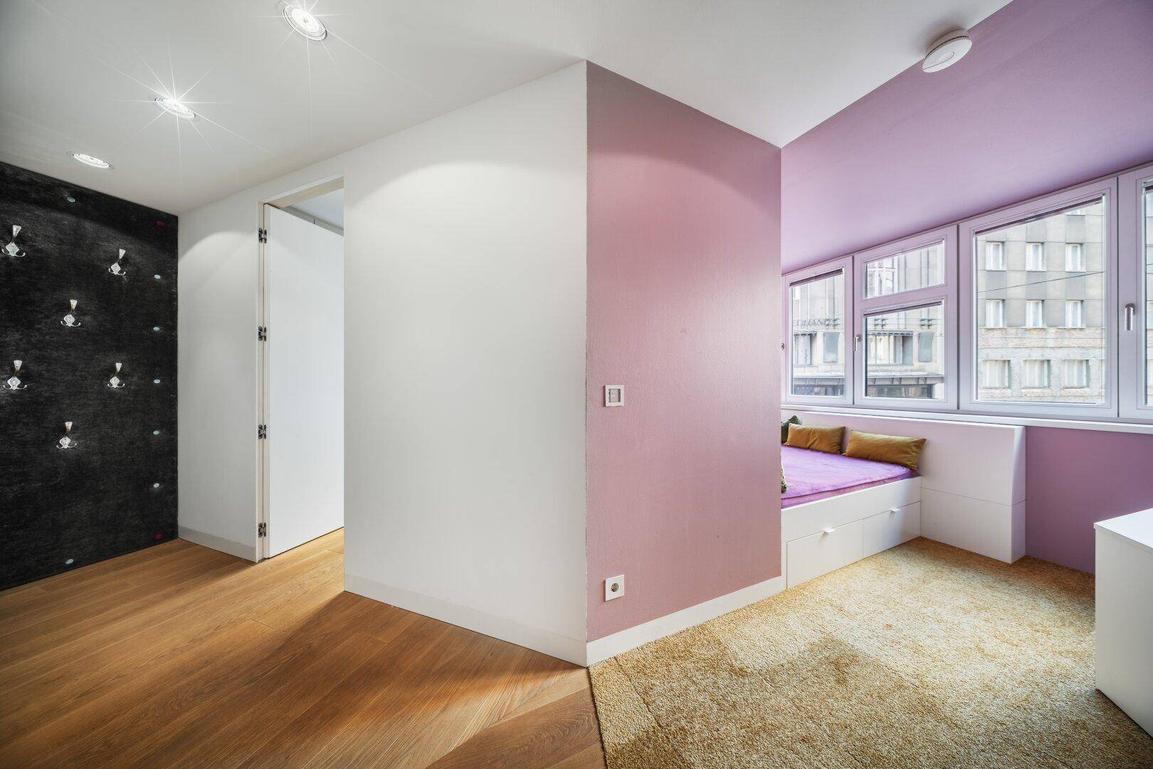 Heller Flur mit Holzboden, der zu einem farbenfrohen Schlafzimmer führt.