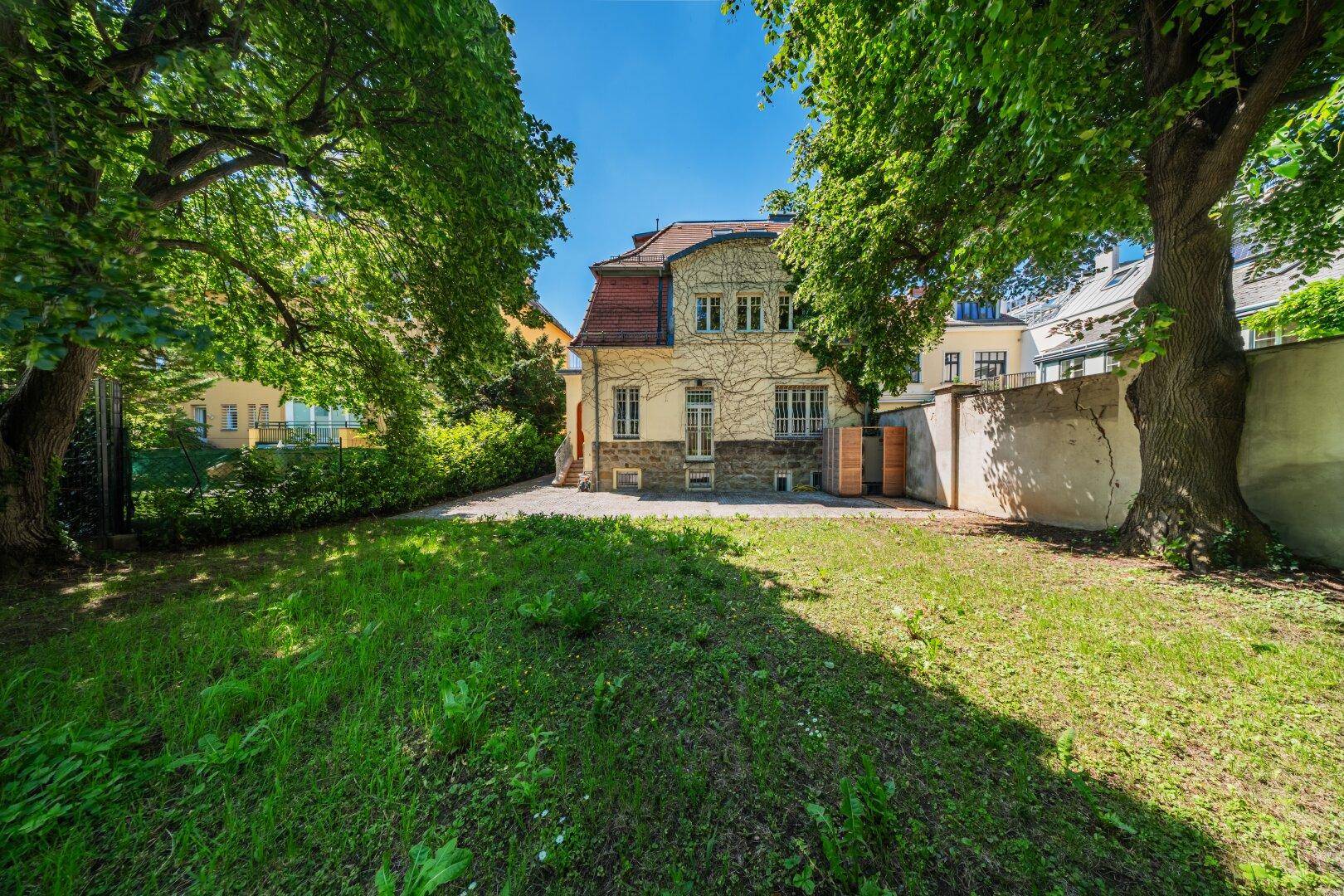 Großer Gartenbereich mit altem Baumbestand und Blick auf die historische Gebäudefassade.