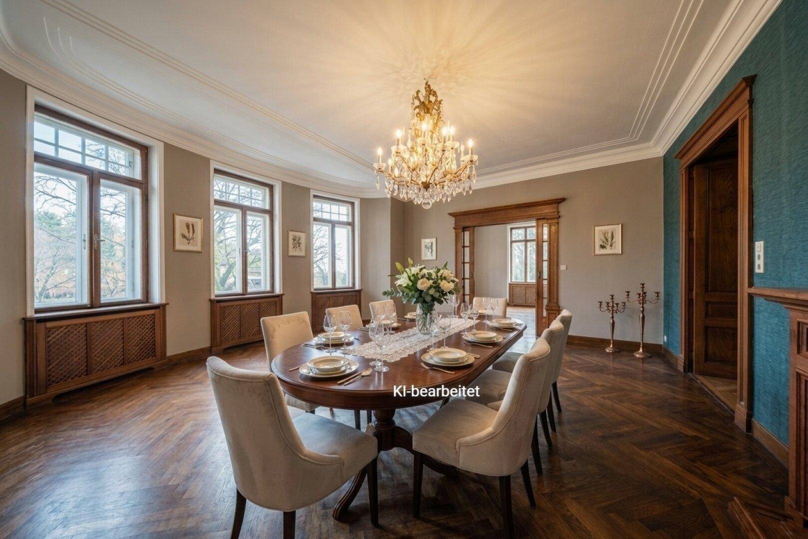 Ein elegantes Esszimmer mit dunklem Fischgrätparkett, Kronleuchter und einem großen Esstisch.