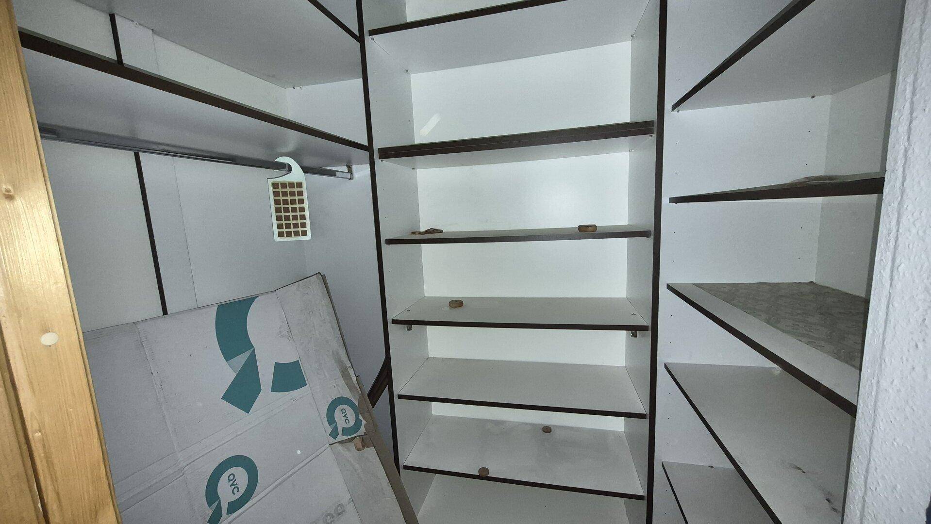 Leerer begehbarer Kleiderschrank mit einfachen Regalen und Kleiderstange.