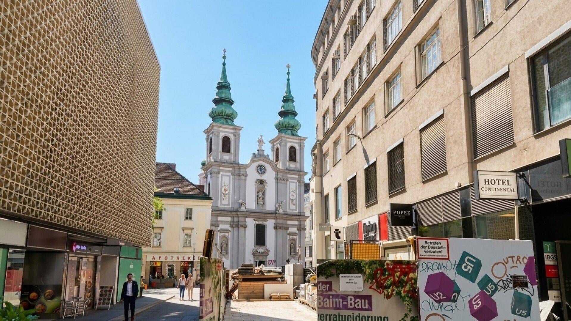 Stadtansicht mit einer historischen Kirche im Hintergrund und Gebäuden entlang der Straße.