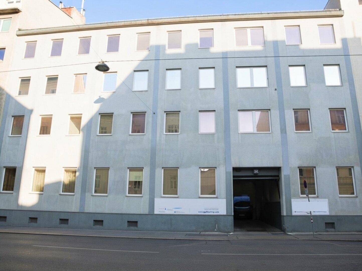 Fassade eines mehrstöckigen Gebäudes mit zahlreichen Fenstern und einer Einfahrt.