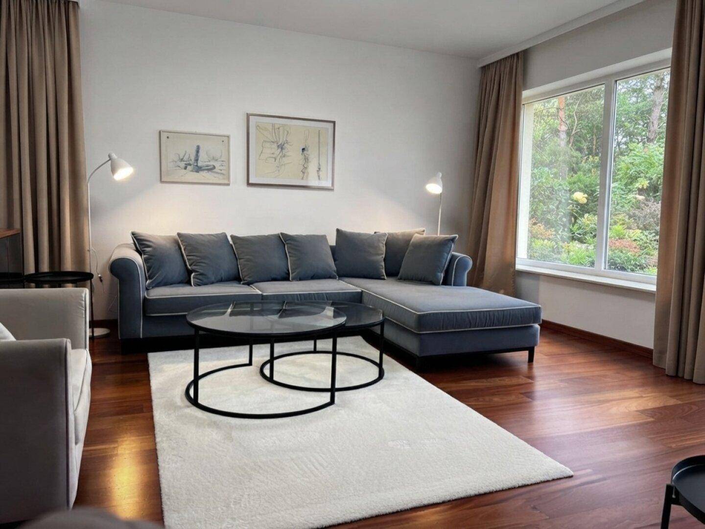 Gemütliches Wohnzimmer mit großem Ecksofa, Holzboden und Blick ins Grüne.