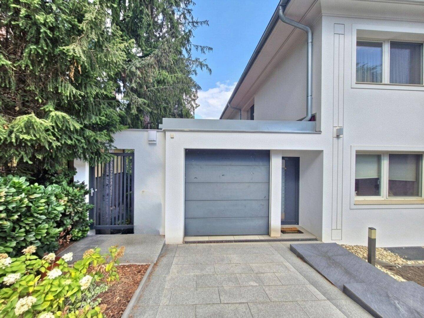 Eingangsbereich des Hauses mit Garage, gepflasterter Auffahrt und seitlichem Zugang.