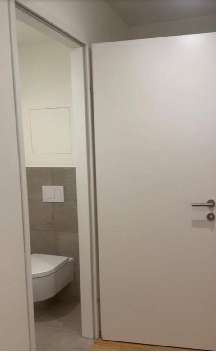 Modernes Gäste-WC mit wandhängender Toilette und stilvollen Fliesen an den Wänden.