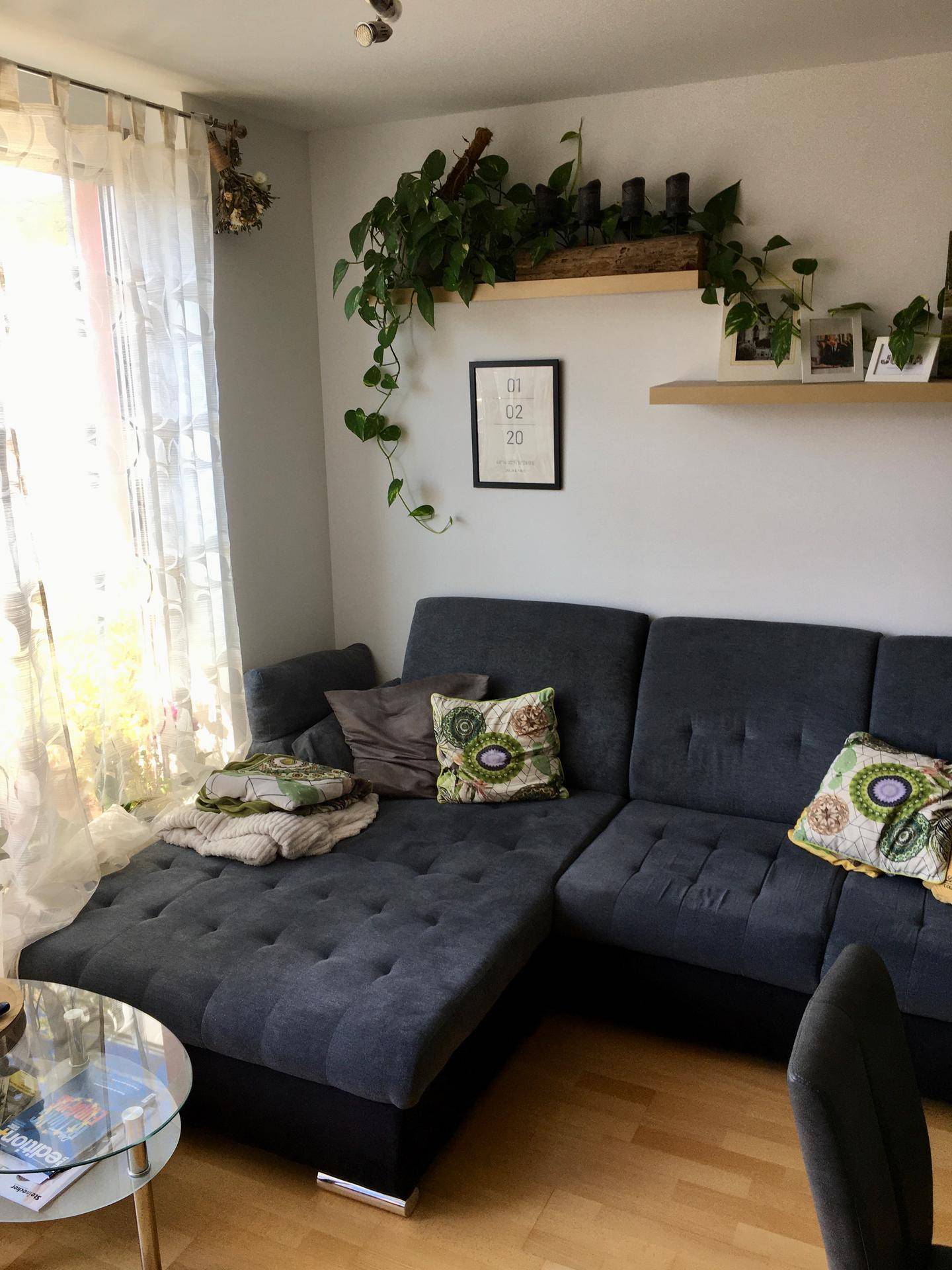 Gemütliches Wohnzimmer mit großem Ecksofa, Holzboden und viel Tageslicht.