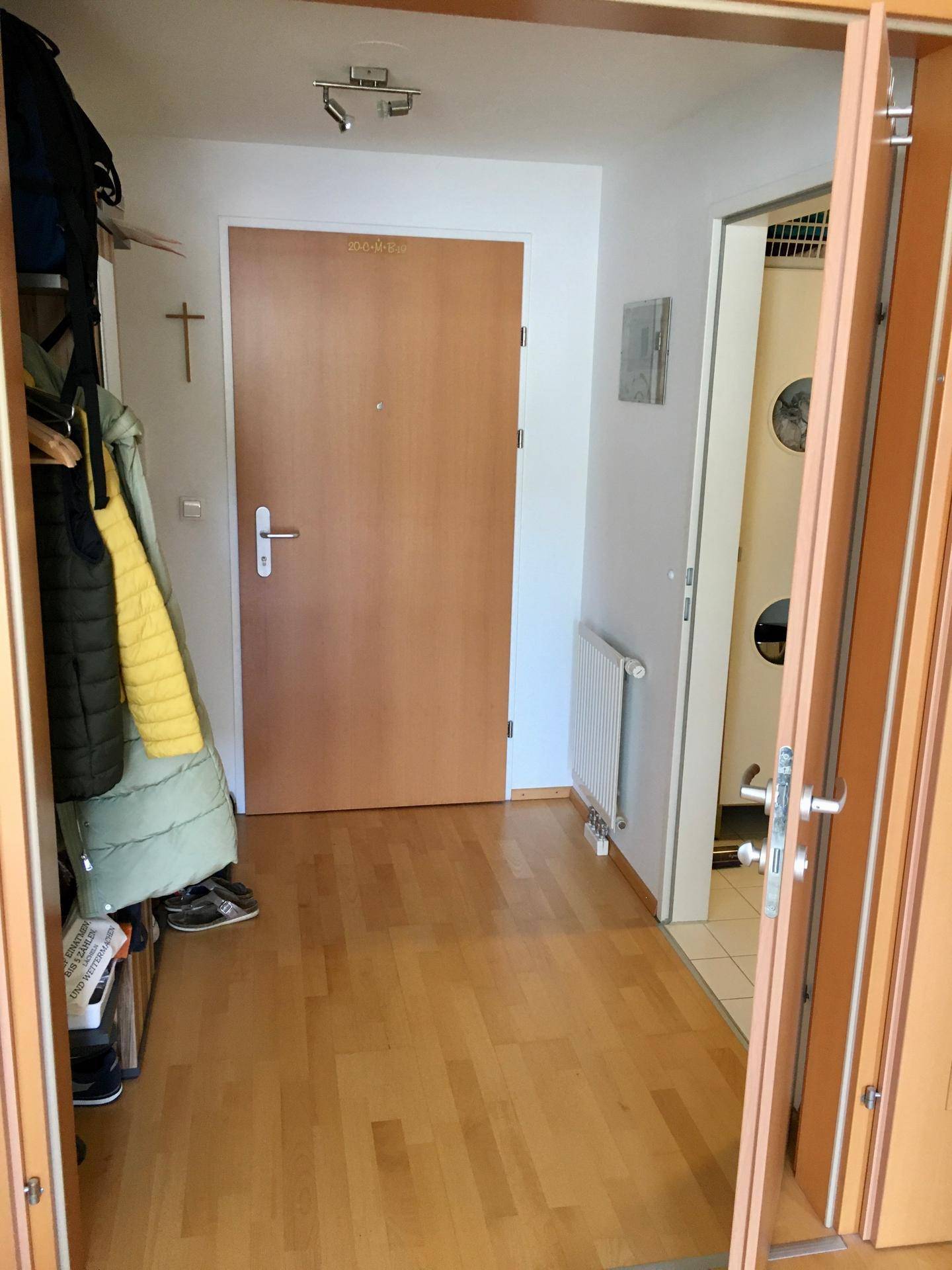 Heller Flur mit Holzboden, Garderobe und Zugang zu weiteren Räumen.