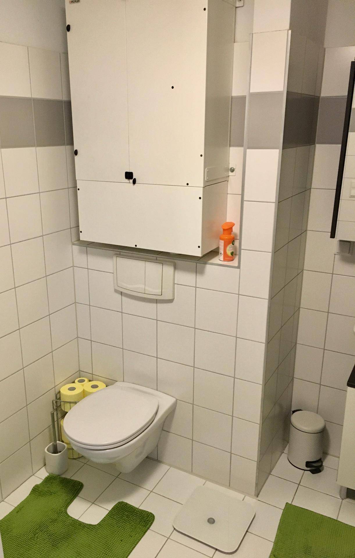 Kleines WC mit Wand-WC, Fliesenboden und praktischem Wandschrank.