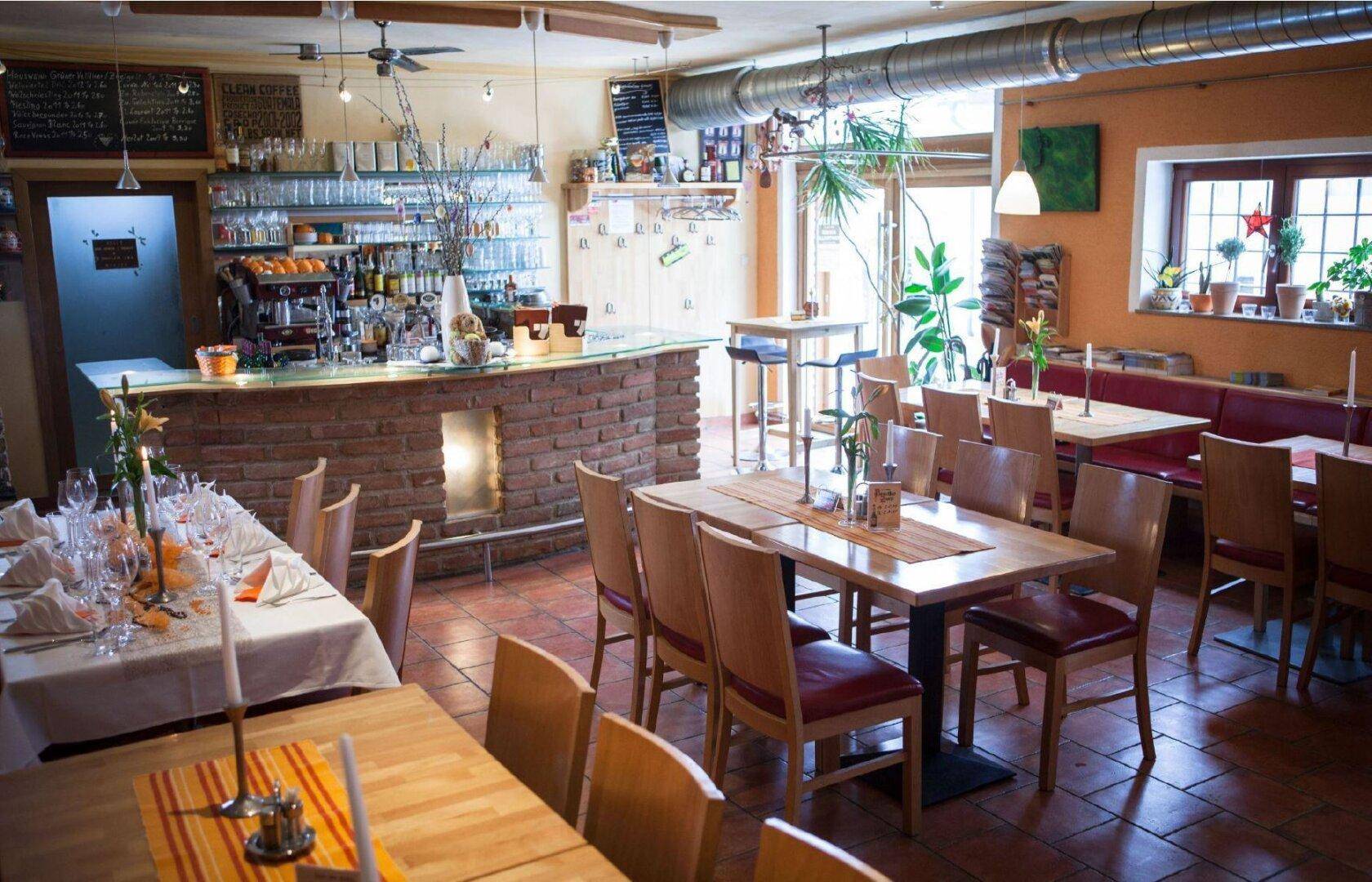 Rustikaler Restaurantbereich mit Ziegeltheke, Holztischen und Fliesenboden, gemütlich eingerichtet.