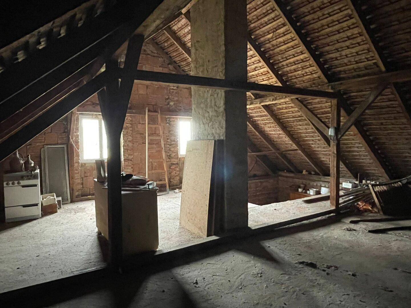 Unausgebauter Dachboden mit sichtbaren Holzbalken und Dachschrägen, der Ausbaupotenzial bietet.