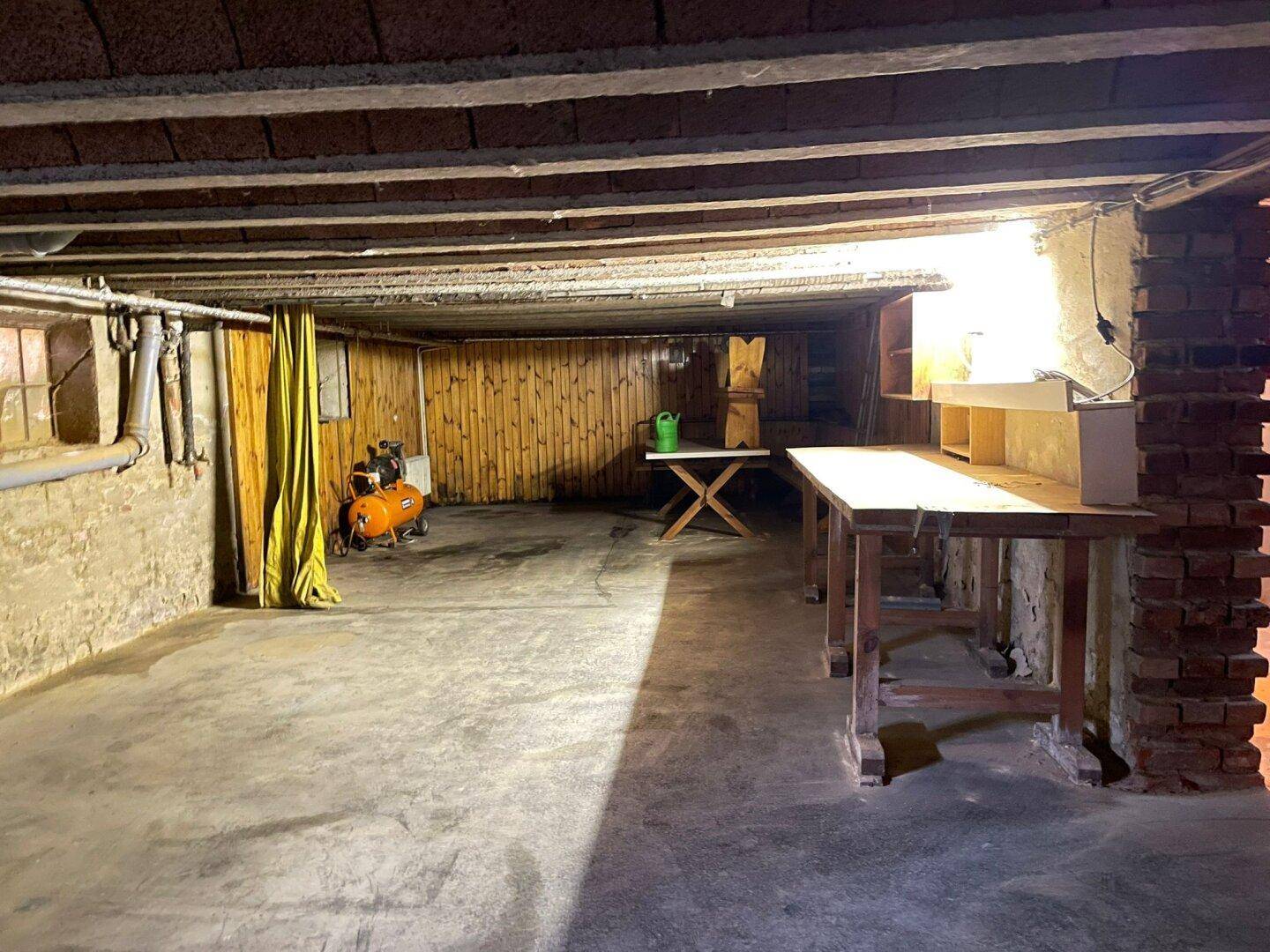 Kellerraum mit Werkbank und Holzverkleidung, der als Arbeits- oder Hobbyraum genutzt werden kann.