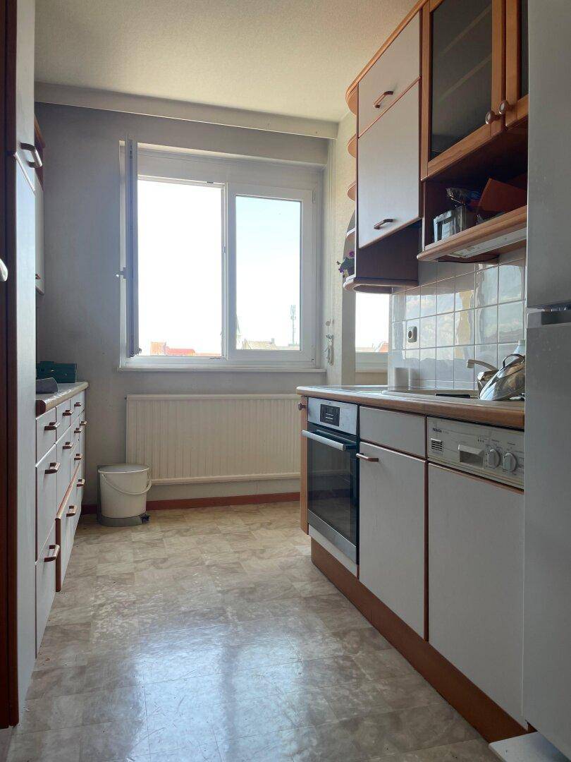 Funktionale Küche mit weißen Schränken, integrierten Geräten und Fenster für Tageslicht.