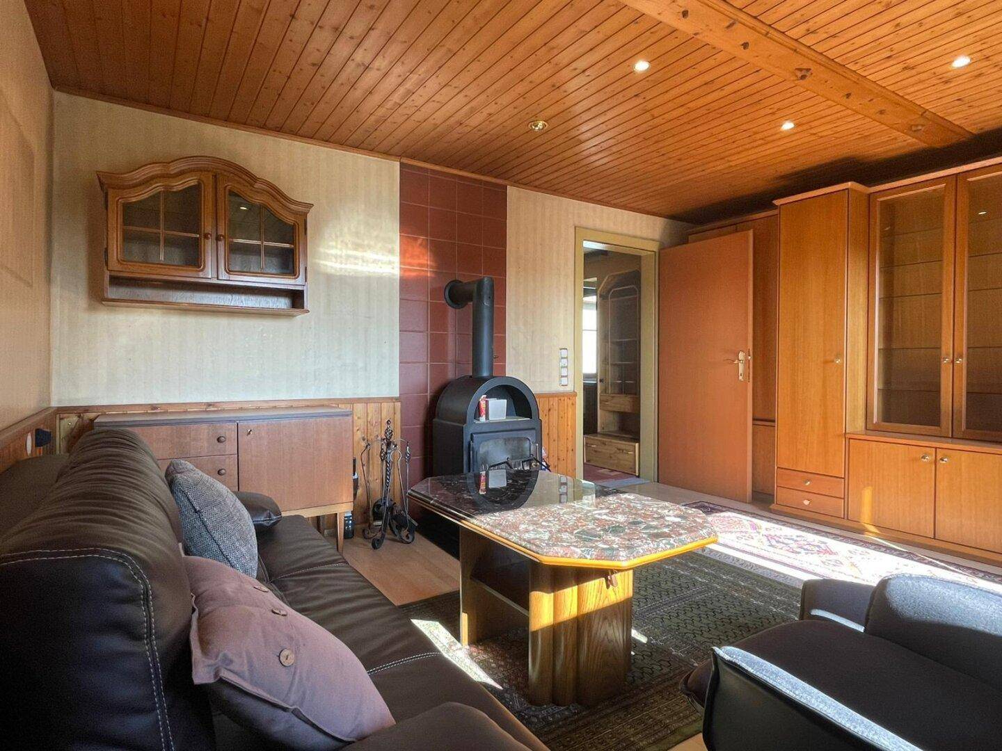 Wohnzimmer mit Holzbalkendecke, Parkettboden und einem gemütlichen Holzofen als Wärmequelle.