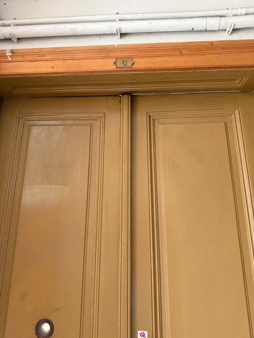 Detailaufnahme einer braunen Holztür mit der Nummer 8.