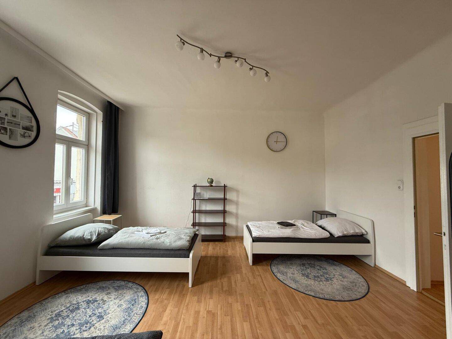 Geräumiges Schlafzimmer mit zwei Betten, Holzboden und Blick auf die Stadt.