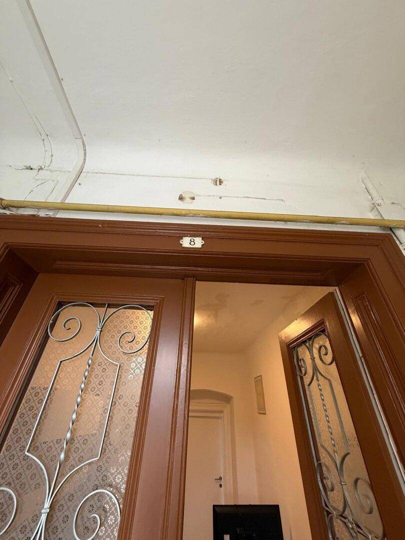 Detailaufnahme einer braunen Holztür mit dekorativen Glaseinsätzen und der Nummer 8.