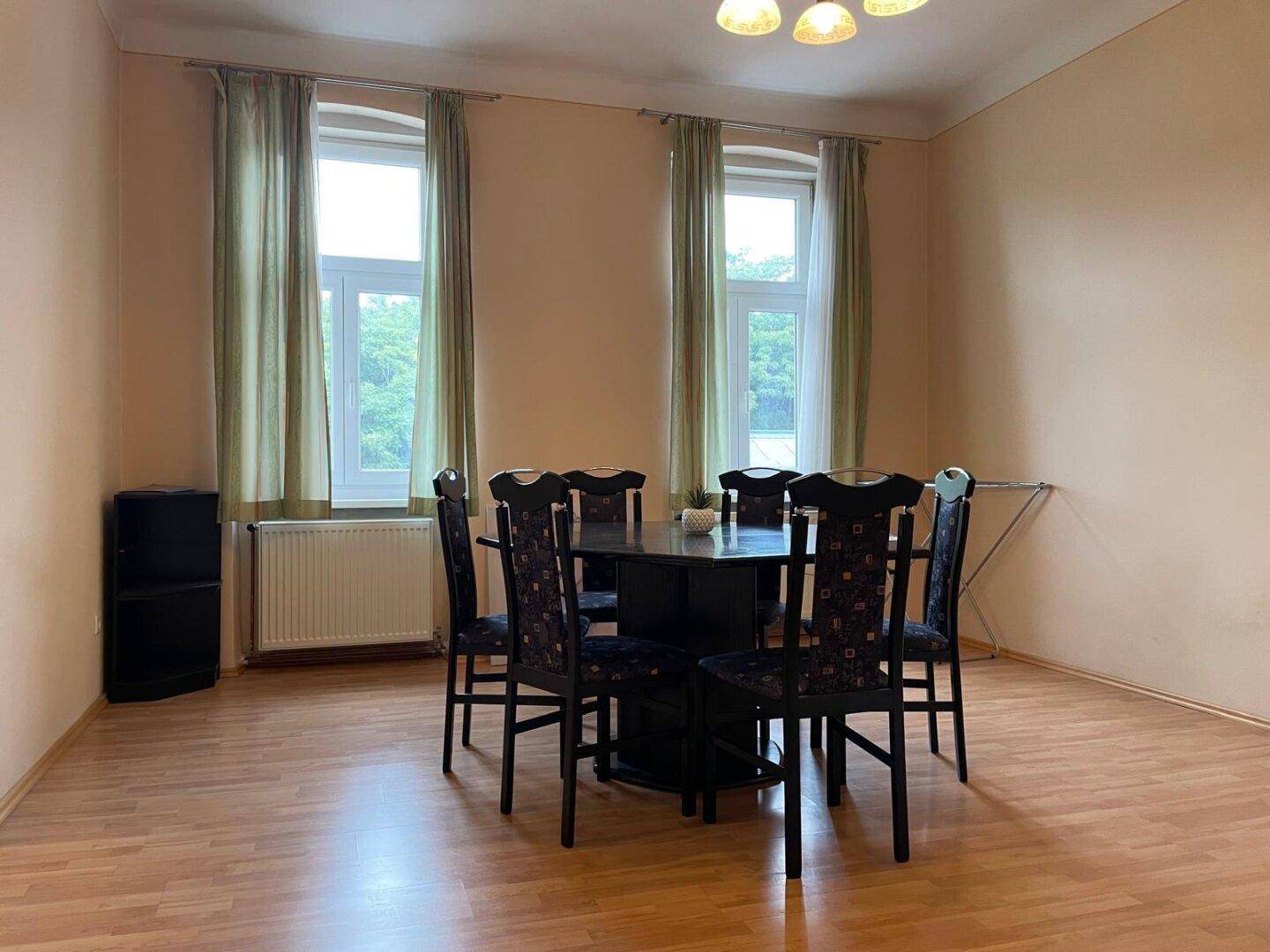 Geräumiger Essbereich mit großem Tisch, Stühlen und zwei Fenstern.