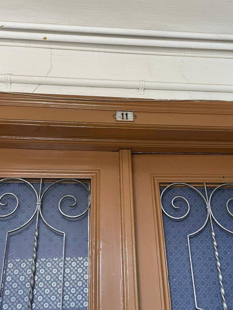 Detailaufnahme einer braunen Holztür mit Glaseinsätzen und der Nummer 11.