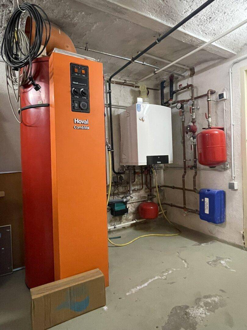 Heizraum im Keller mit modernen Heizungsanlagen und einem Warmwasserspeicher für effiziente Versorgung.