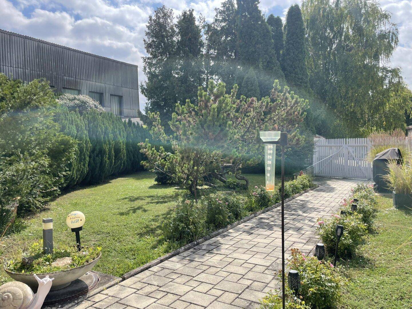Gepflegter Vorgarten mit Rasenfläche, einem gepflasterten Weg und Ziersträuchern, die zum Haus führen.