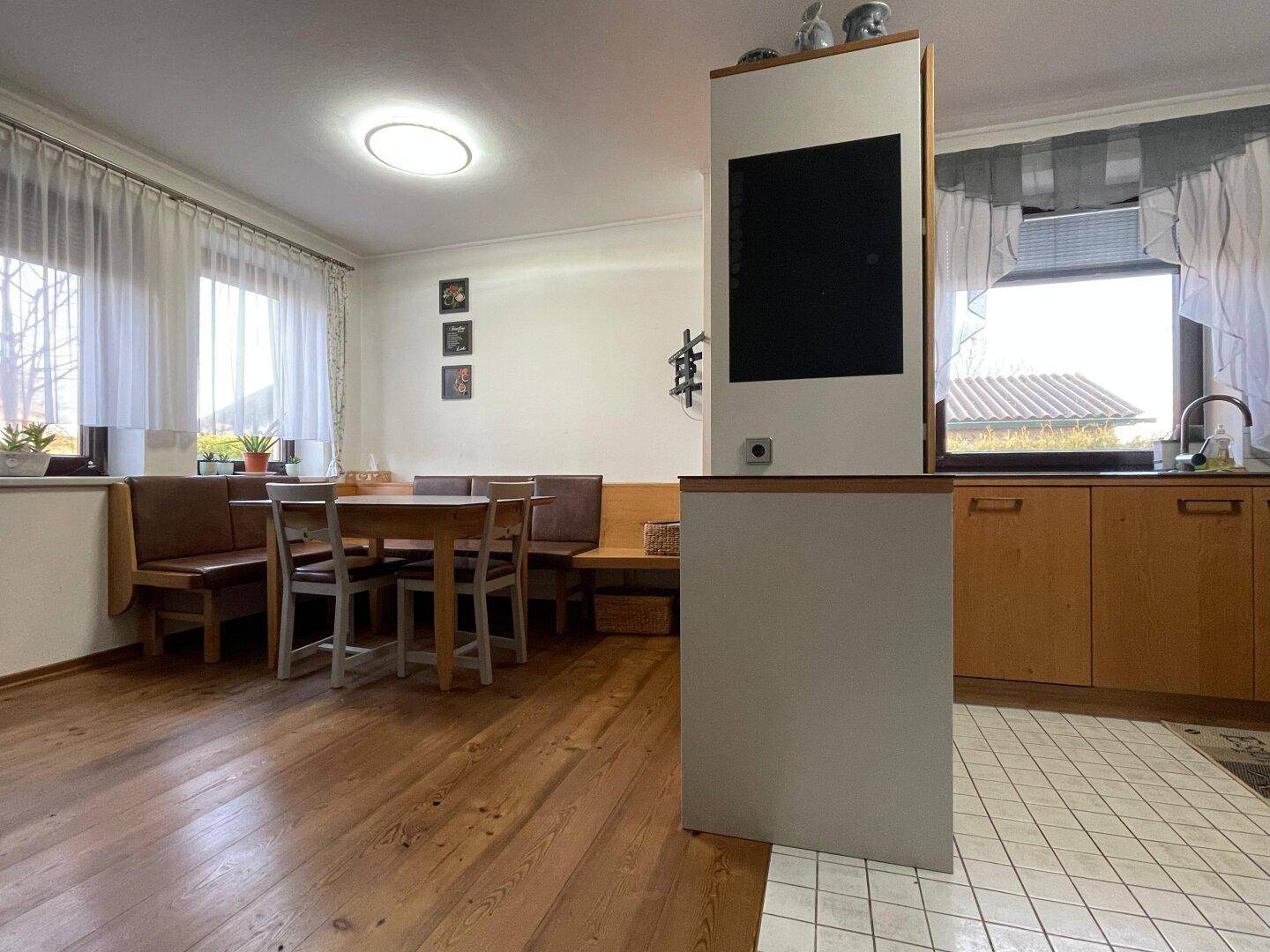 Offener Wohn- und Essbereich mit Holzboden, Eckbank und Übergang zur Küche.