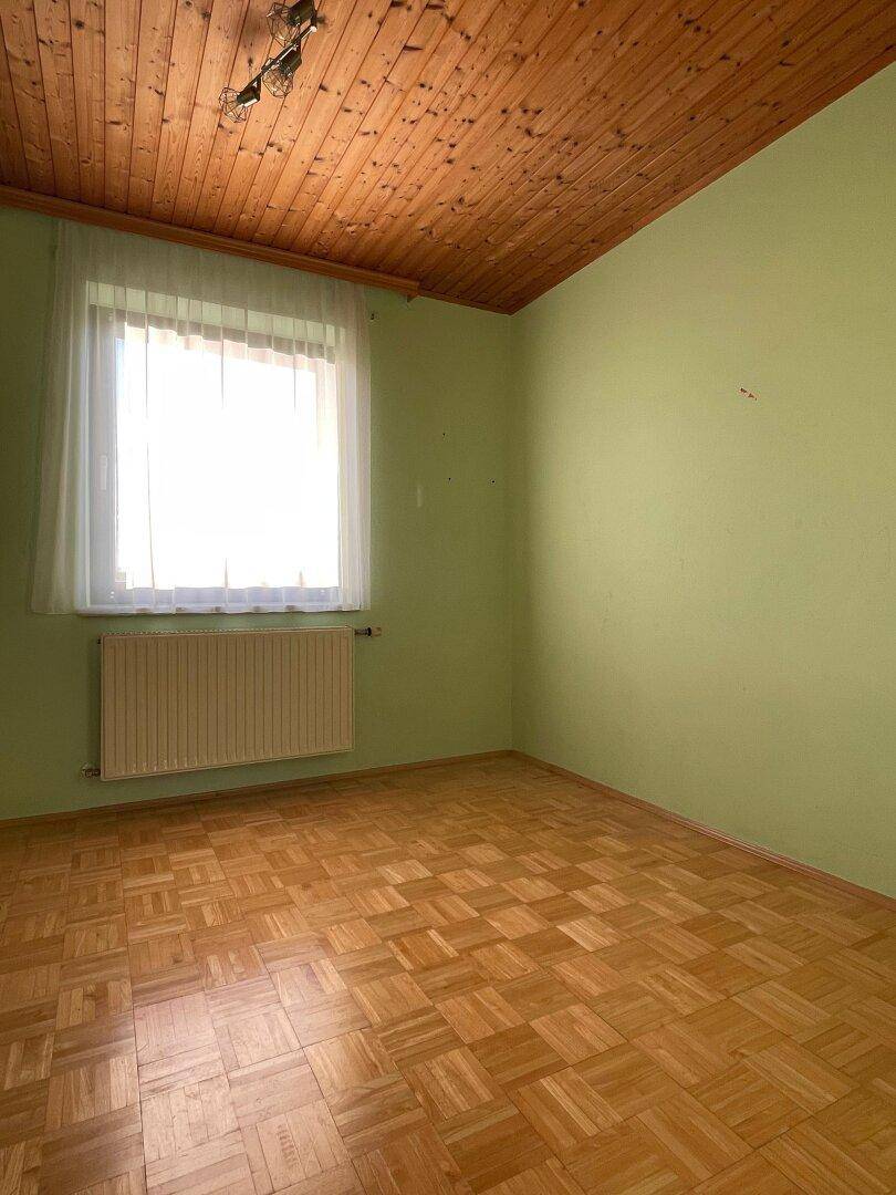 Schlafzimmer mit hellgrünen Wänden, Holzdecke und klassischem Parkettboden.