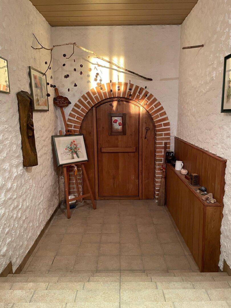 Rustikaler Eingangsbereich mit Ziegelbogen, Holztür und weiß getünchten Wänden.