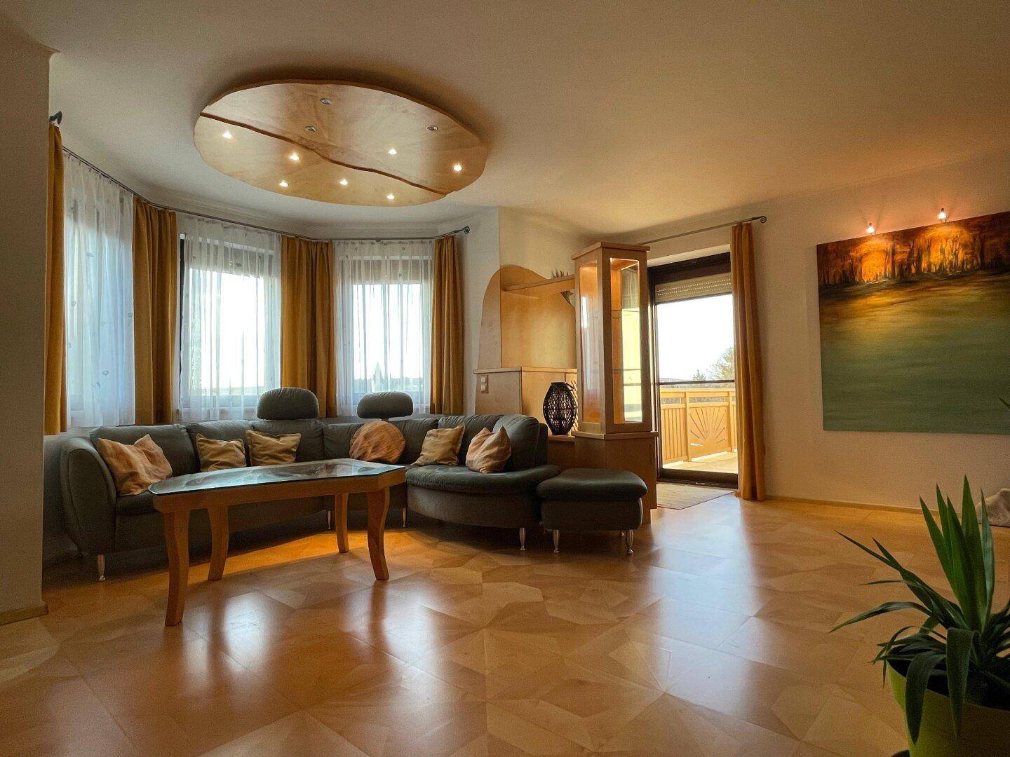 Helles Wohnzimmer mit bequemer Sitzecke, Parkettboden und Zugang zum Balkon.